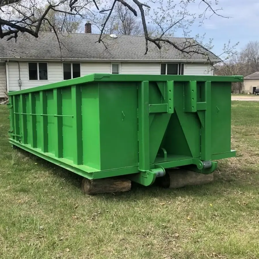 Roll-off dumpster on wood blocks beside a house